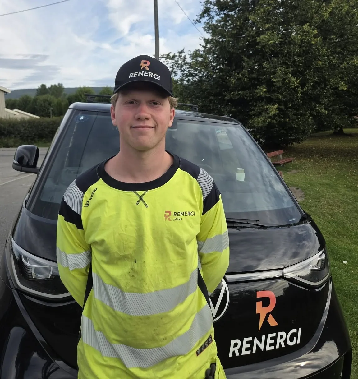 Ansatt i Renergi Infra foran en av firmabilene med Renergi-logoen