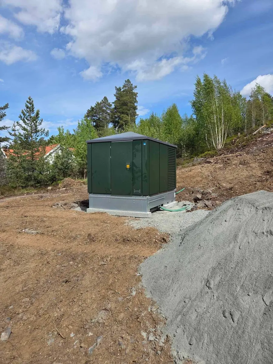 Grønn nettstasjon på en ryddet tomt